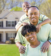 Smiling Mother, Father and child in front of their new home.