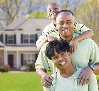 Mother, Father and child with newly purchased home behind them.
