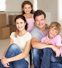 Happy family in front of moving boxes in their new home.